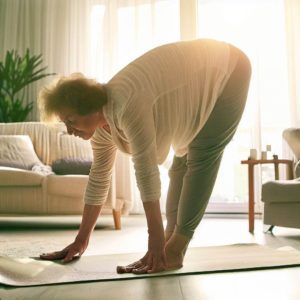 Yoga et Pilates pour la fibromyalgie, une patiente souffrant de fibromyalgie fait des exercices de yoga chez elle le matin.